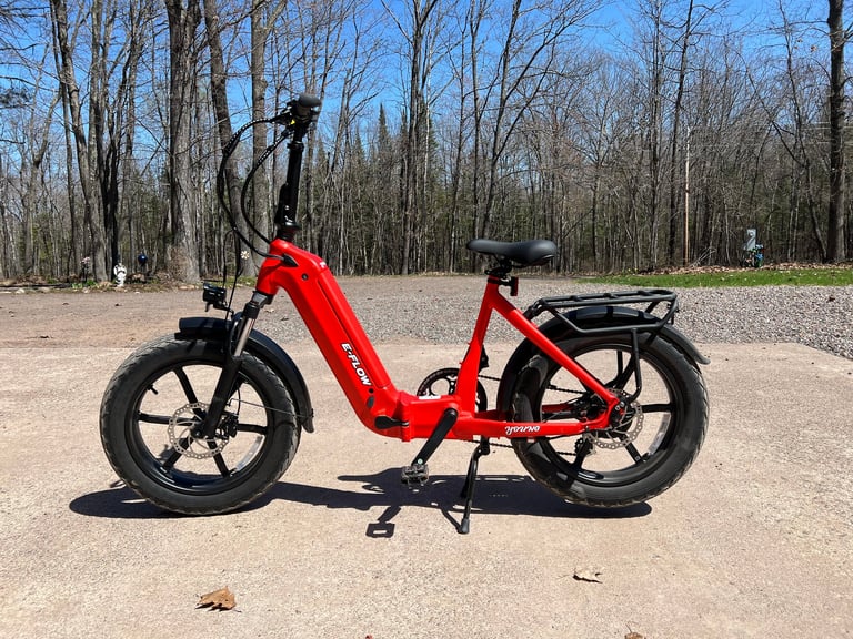 Red electric bike parked on gravel path with bare trees in background